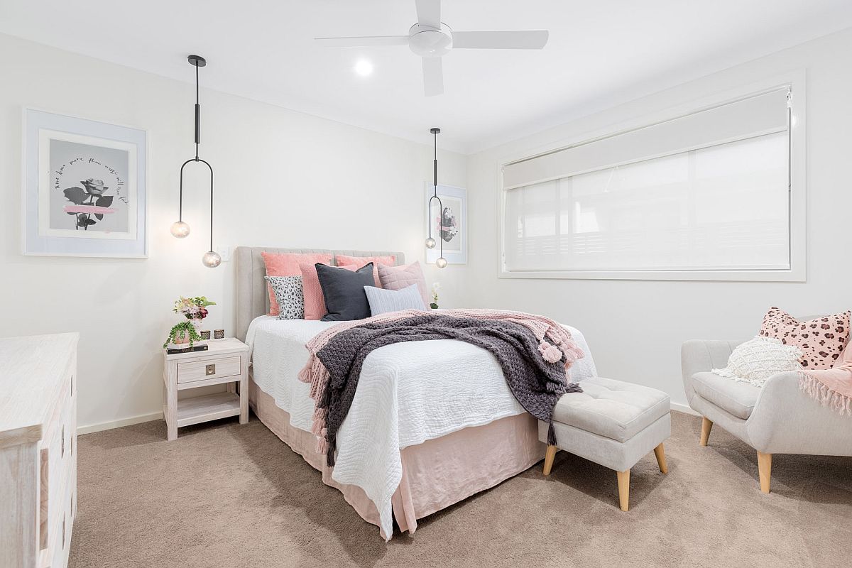 Pillows and accents bring pops of light pink to this Scandinavian style bedroom