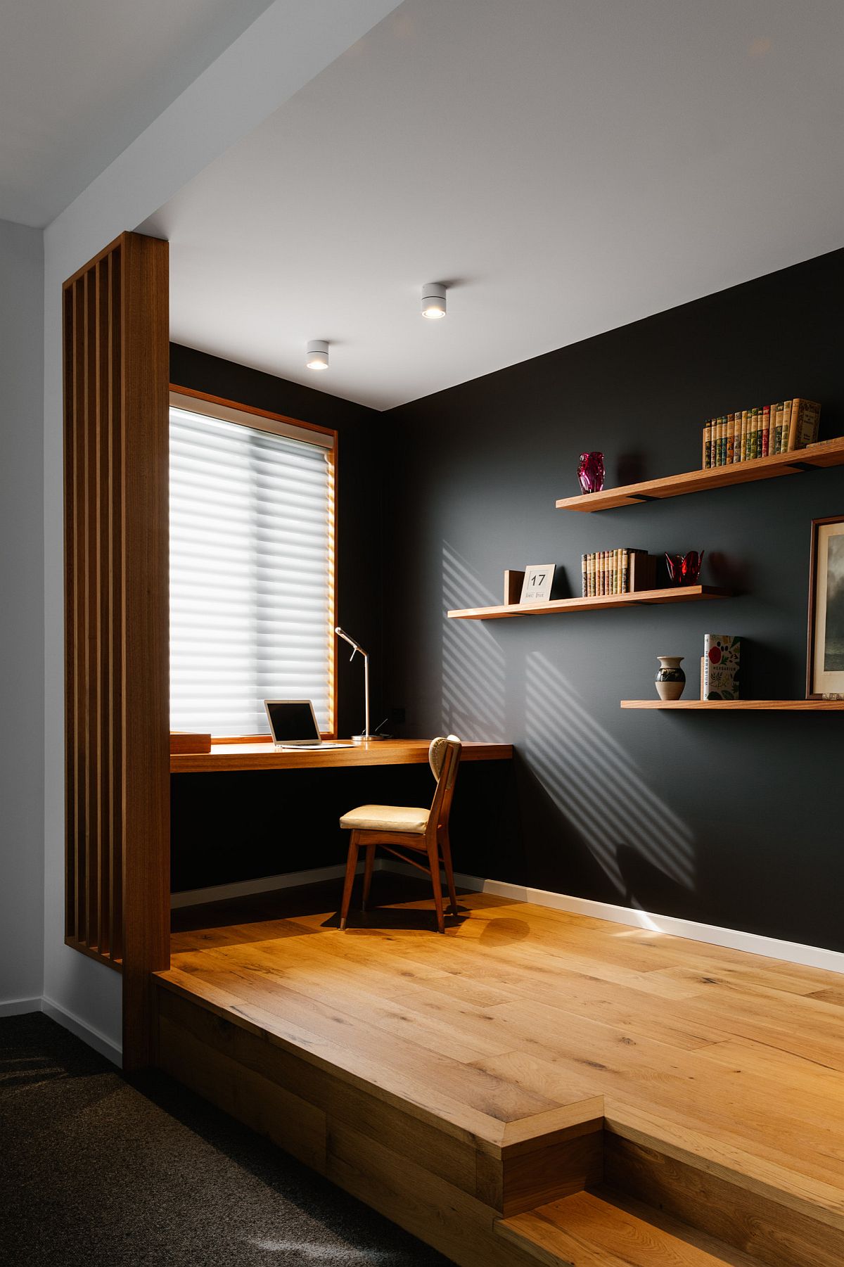 Raised wooden floor delineates this black and wood home office from the living area