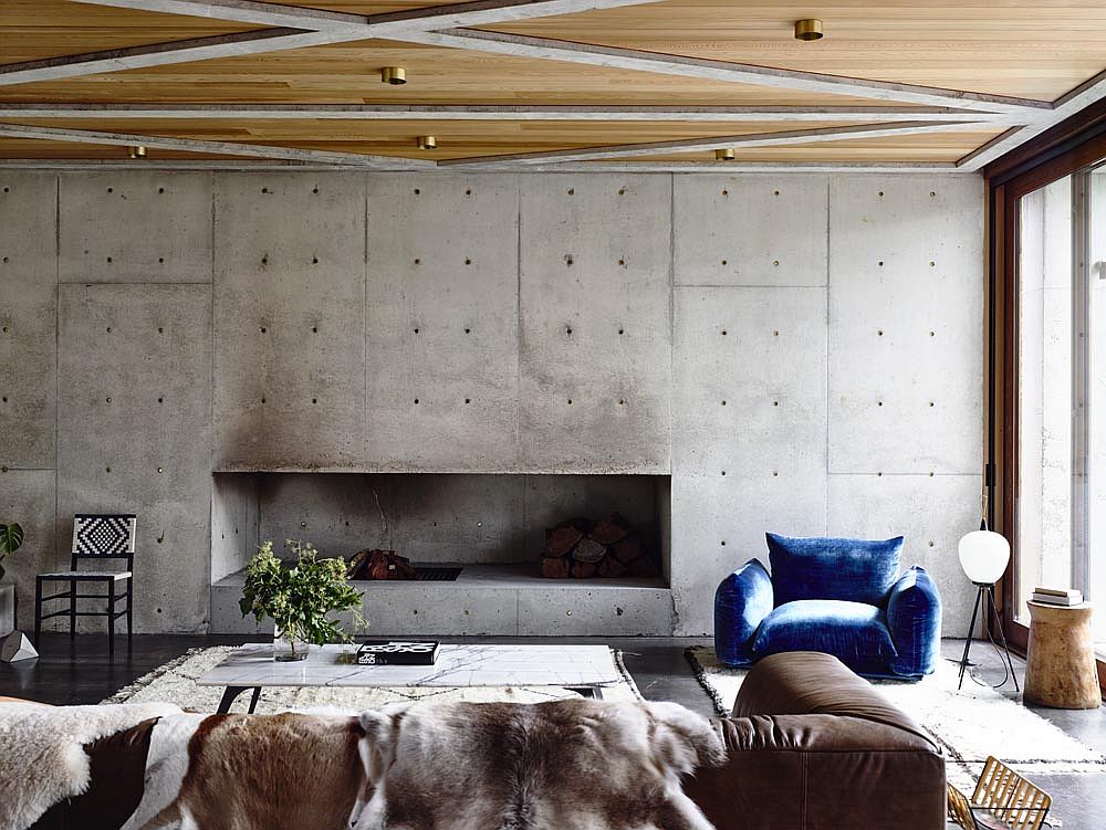 Raw concrete walls in the living room along with wooden ceiling usher in ample textural contrast