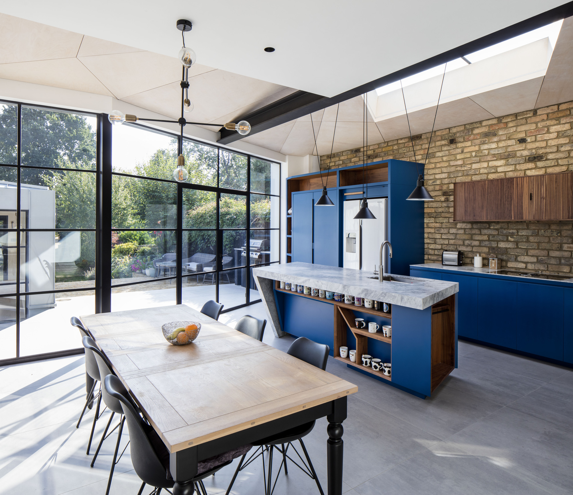 Renovated Victorian home dining area and kitchen with exposed brick wall and blue cabinets