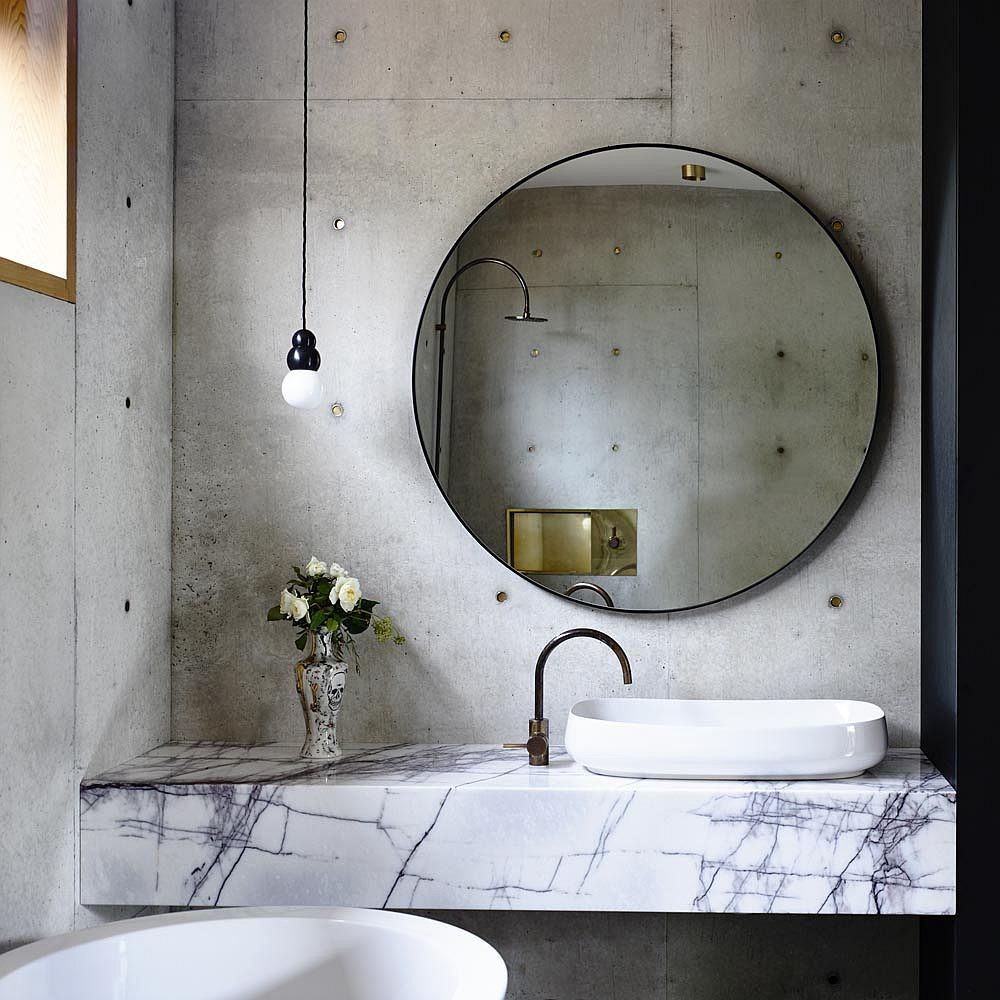 Slim marble vanity in the concrete bathroom creates visual contrast inside the small space