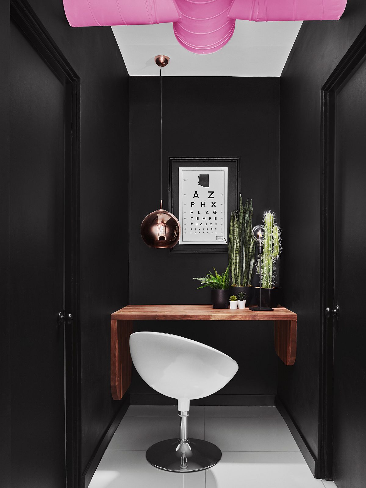 Small black home office with built-in wooden desk and copper pendant light