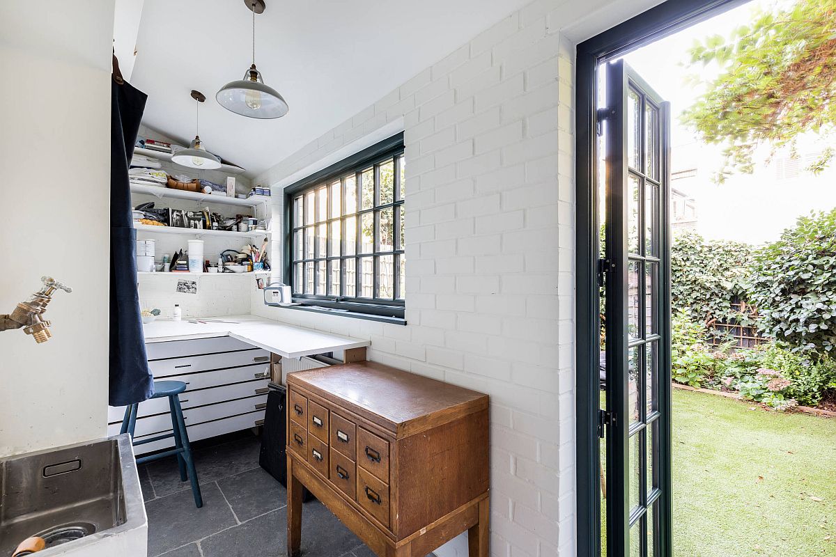 Tiny white craft room with brick walls and crafting desk in the corner