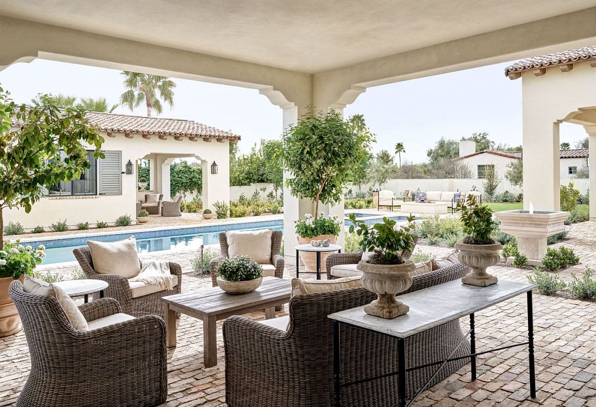 Traditional outdoor sitting space and poolside deck with a lovely pool house next to it