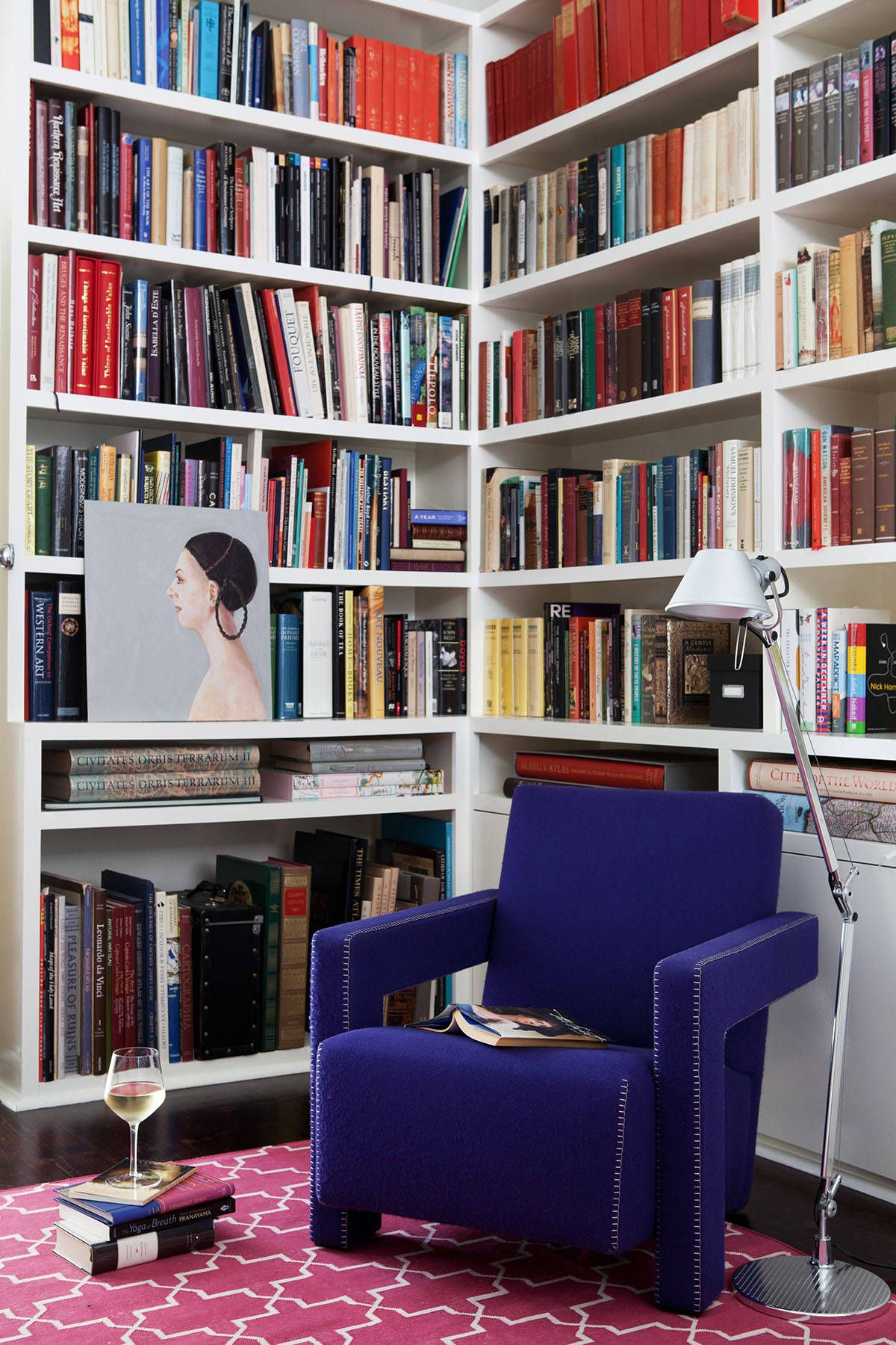 Turning the small corner in the modern Victorian home into a library with bright pink rug, blue chair and ample shelving