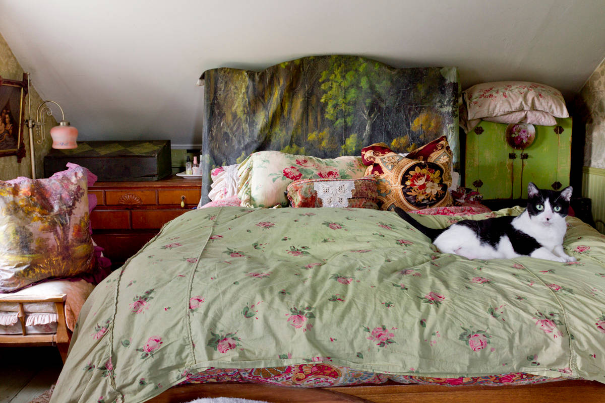 Bedroom with low-level ceiling and a bed with a cat sitting on it.