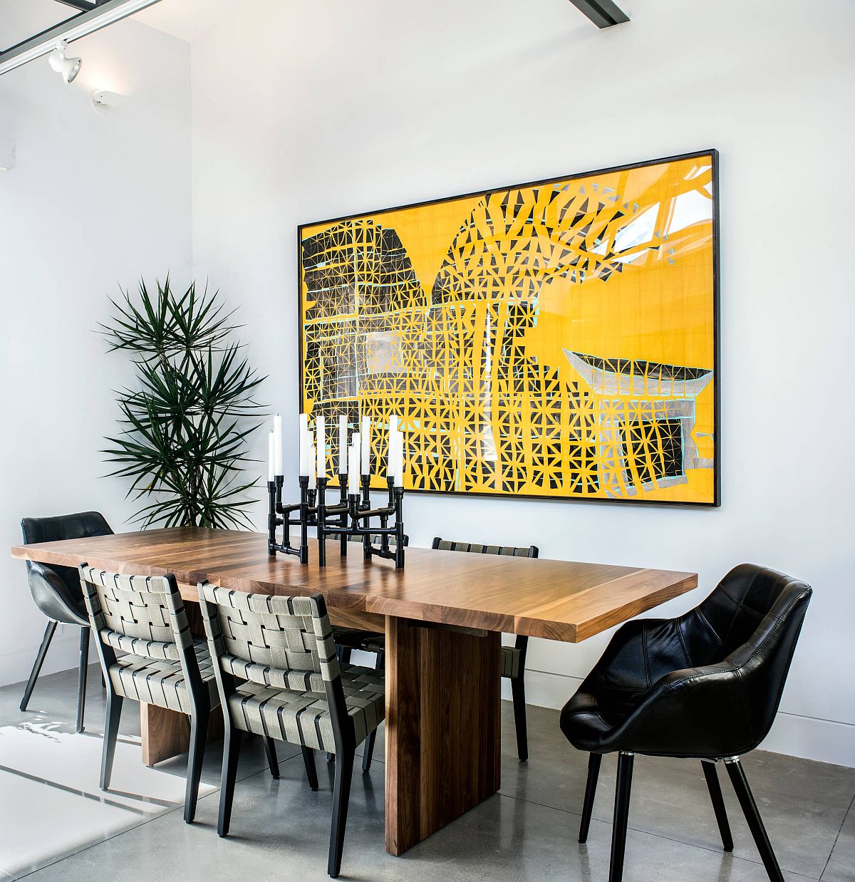 Wall art in this dining room adds bright yellow to a black and white space