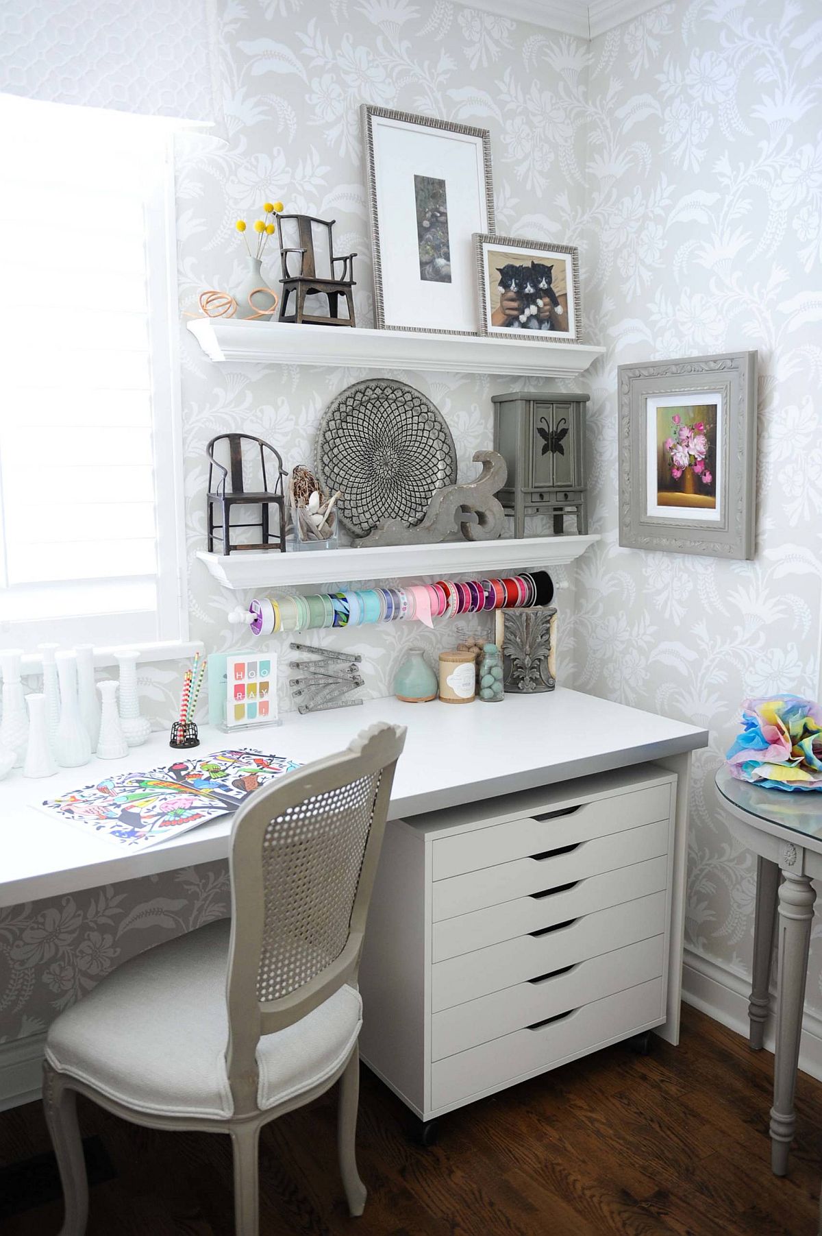 Wallpaper brings floral pattern to this small crafts room in white with clever storage ideas