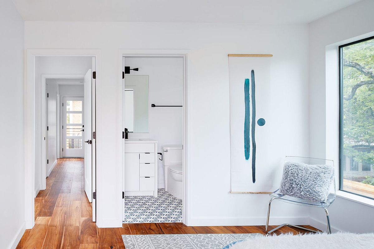 Wooden floor delineates the bedroom from the bathroom next to it with patterned floor tiles