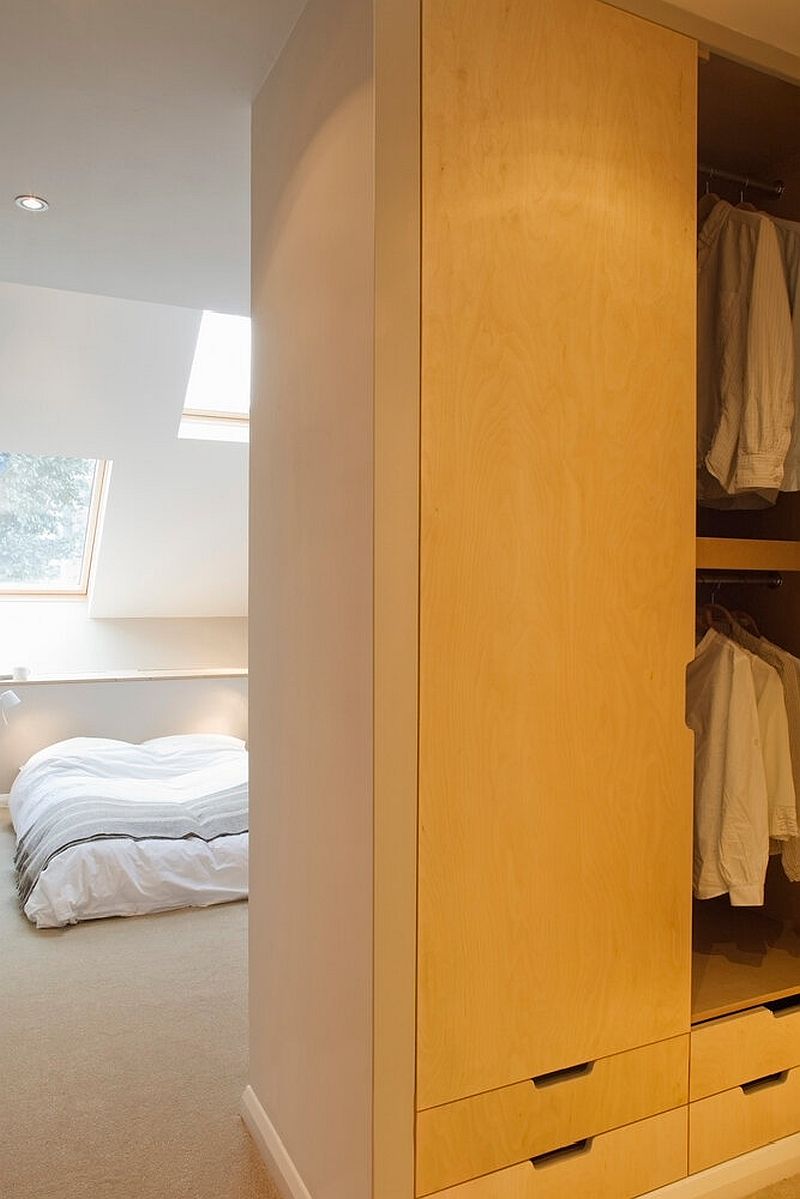 Bespoke wooden closets and wardrobes add storage space while delineating space inside the bedroom