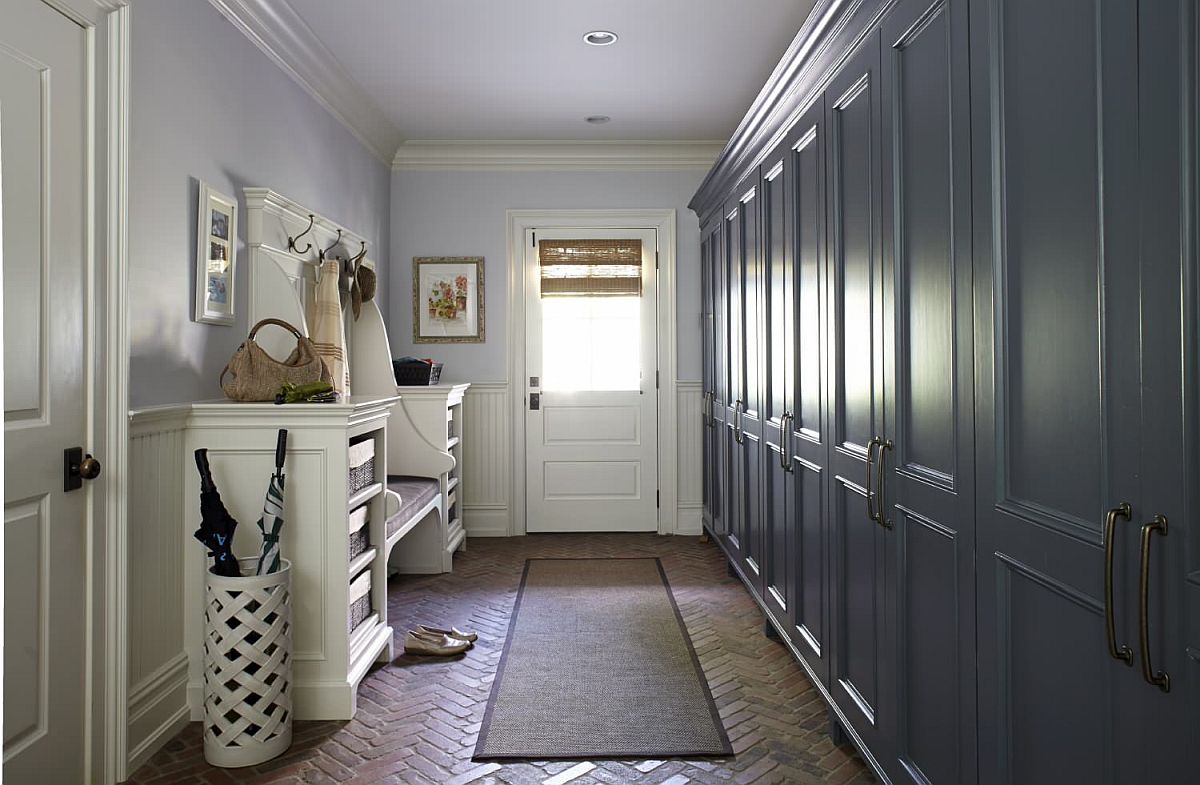 Entryway-of-New-York-home-with-light-blue-walls-dark-grayish-blue-cabinets-and-timeless-brick-floor-67792