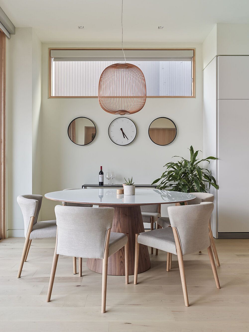 Gorgeous and minimal wood and white dining area with indoor plant and snazzy pendant light