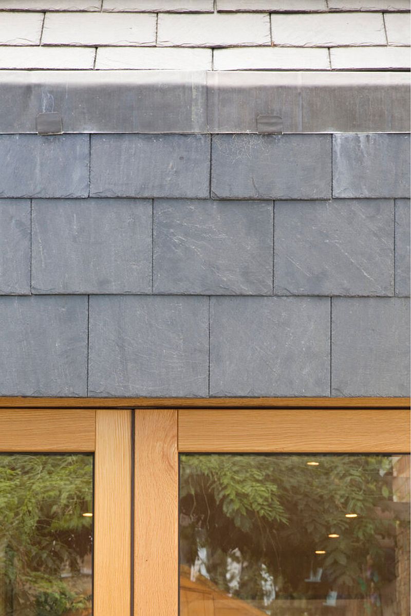 Gray tiles along with wood and glass shape this narrow London home on the outside