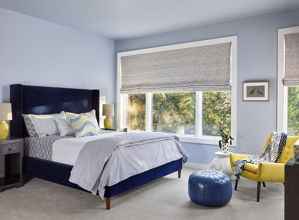 Light blue walls along with the dark blue bed create a tone-on-tone look in the modern bedroom