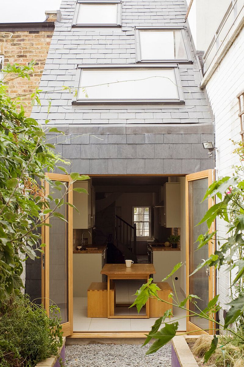 Modern Slim House in London with a gray and wood exterior and a sloped ceiling that has staggered skylight