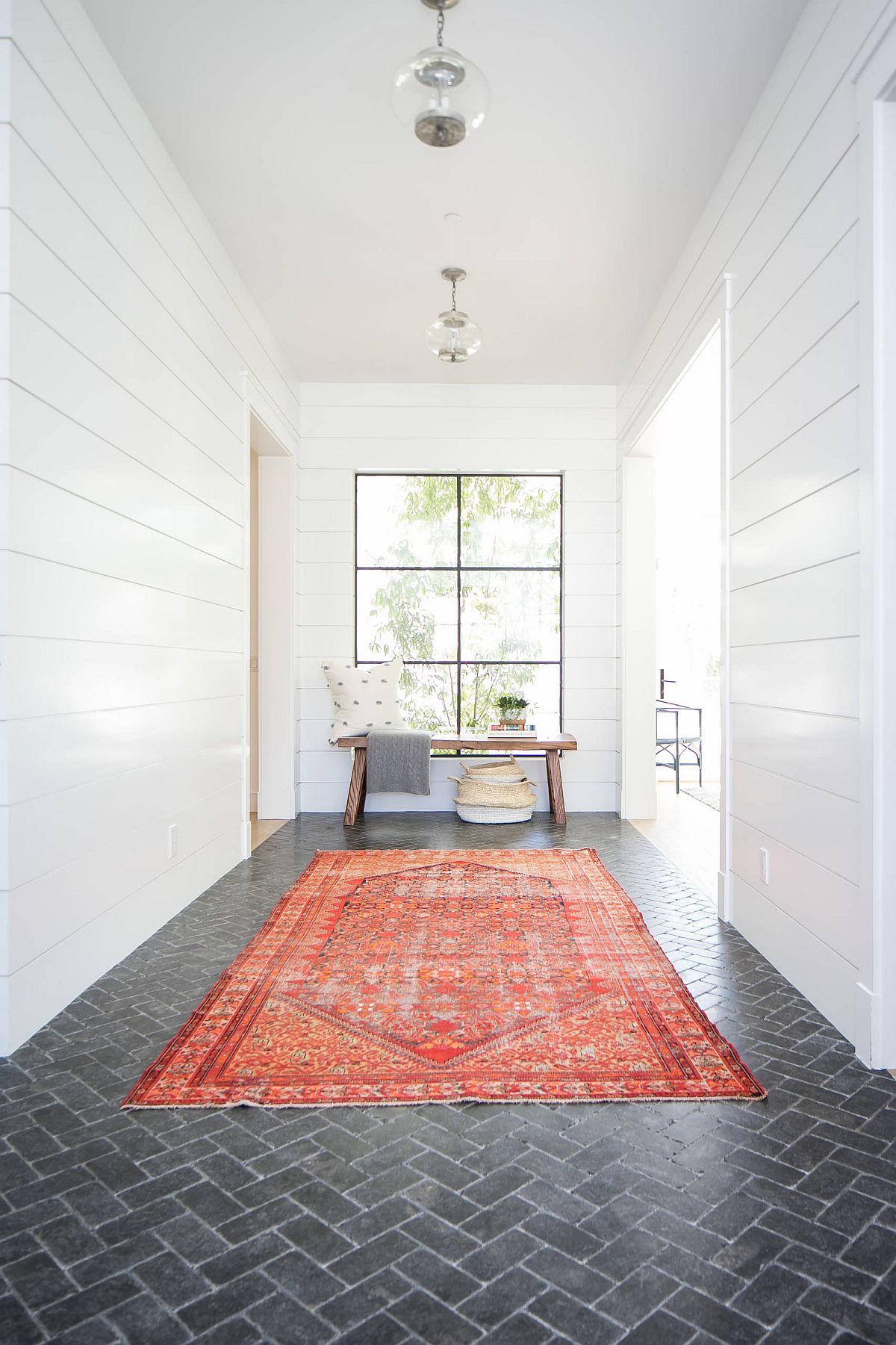 Rug-adds-bright-orange-hue-to-the-neutral-modern-entry-that-has-white-walls-and-dark-gray-brick-floor-39400