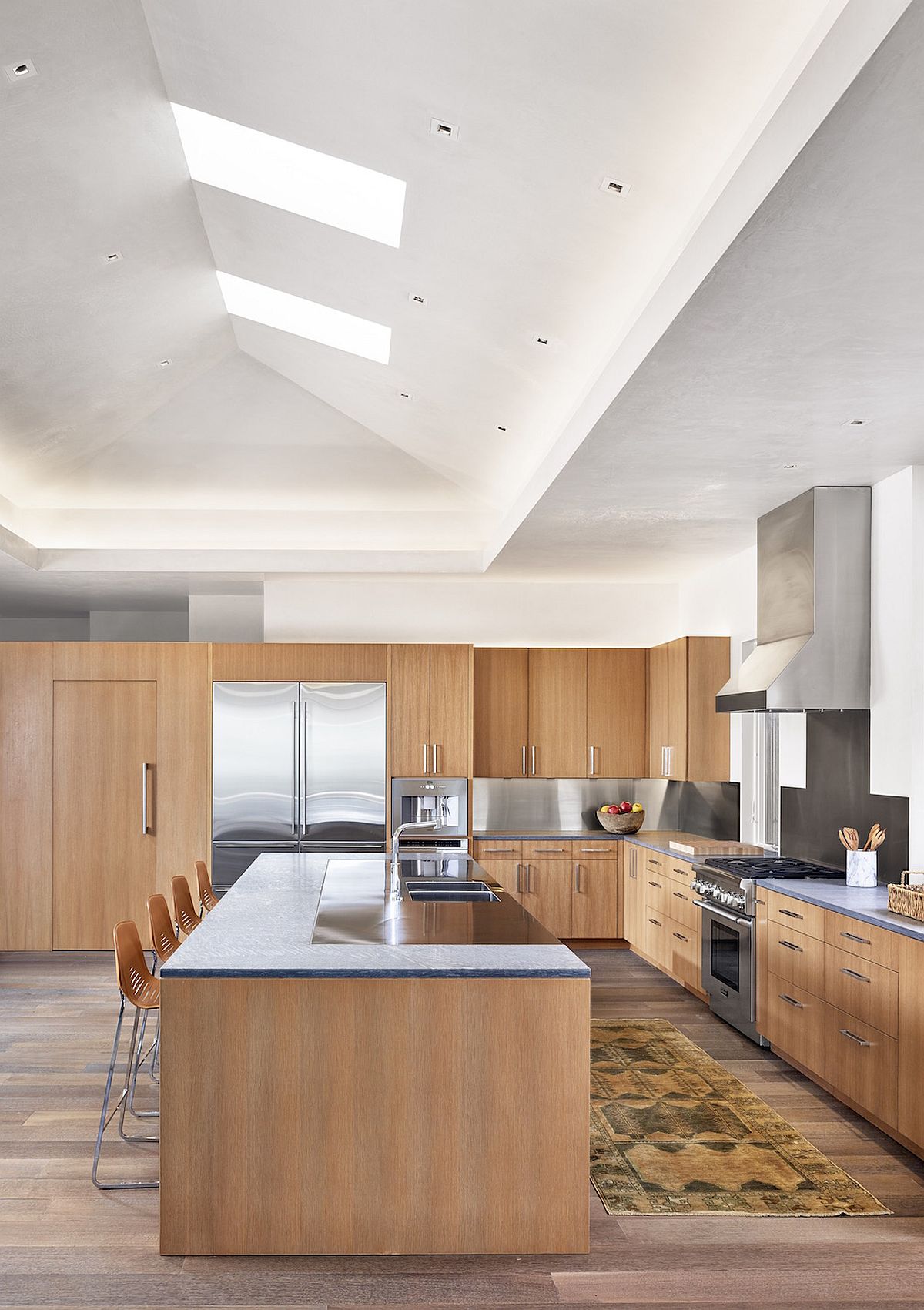 Skylights and glass doors bring a flood of natural light into the double height contemporary kitchen with an air of minimalism