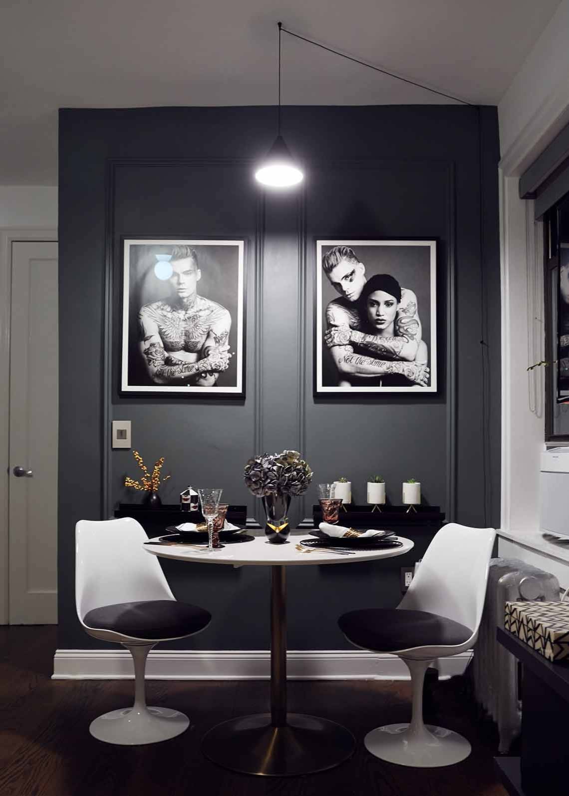 Sophisticated NYC dining room with dark gray walls and framed photographs in the backdrop