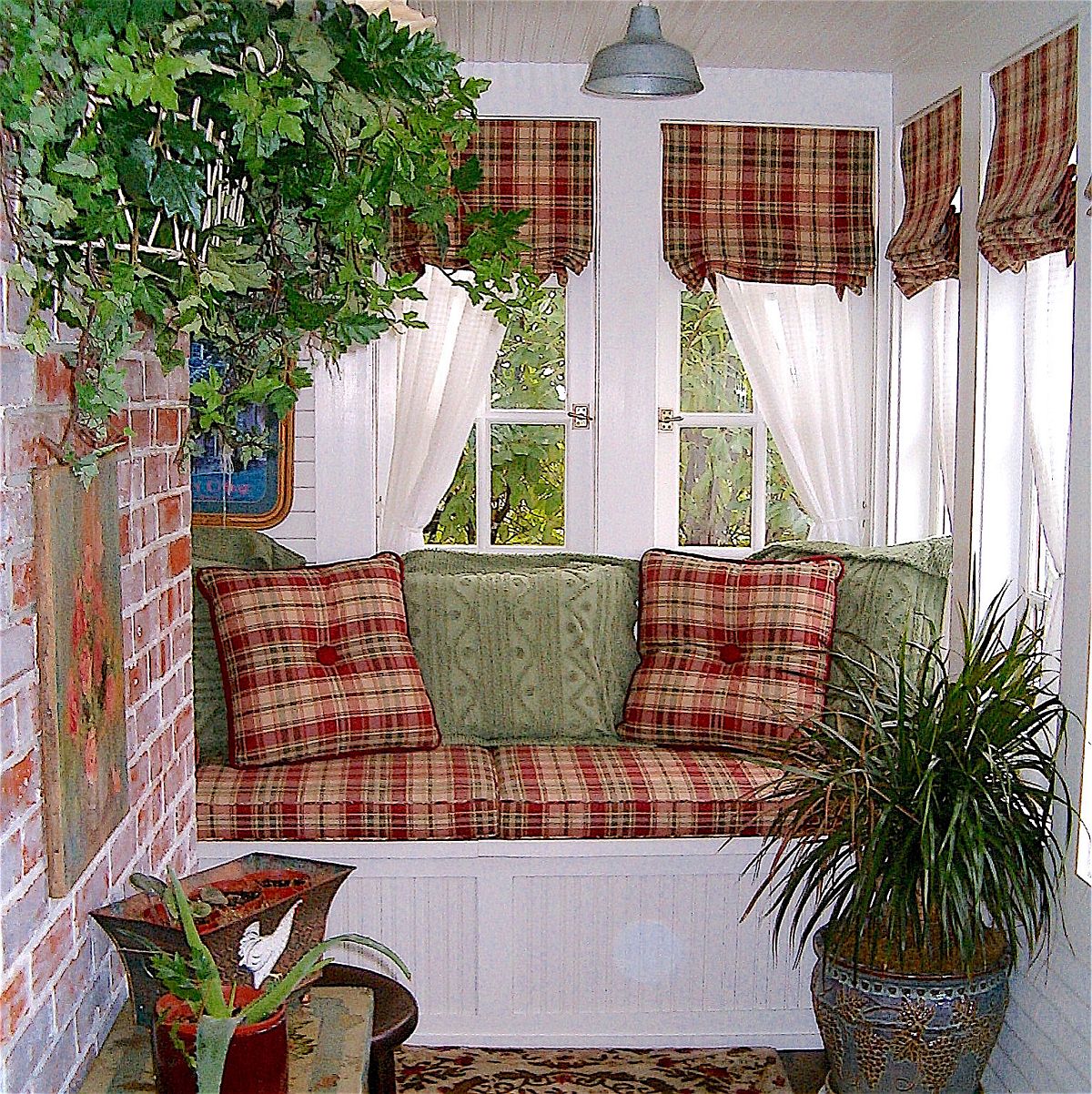 Textiles with plaid pattern add both color and authentic farmhouse appeal to the small sunroom