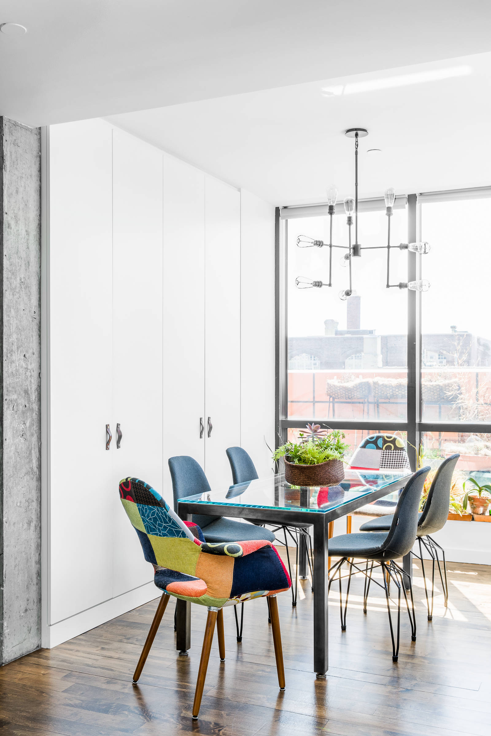 Two multi-colored chairs add contrast to this small contemporary dining room in neutral hues