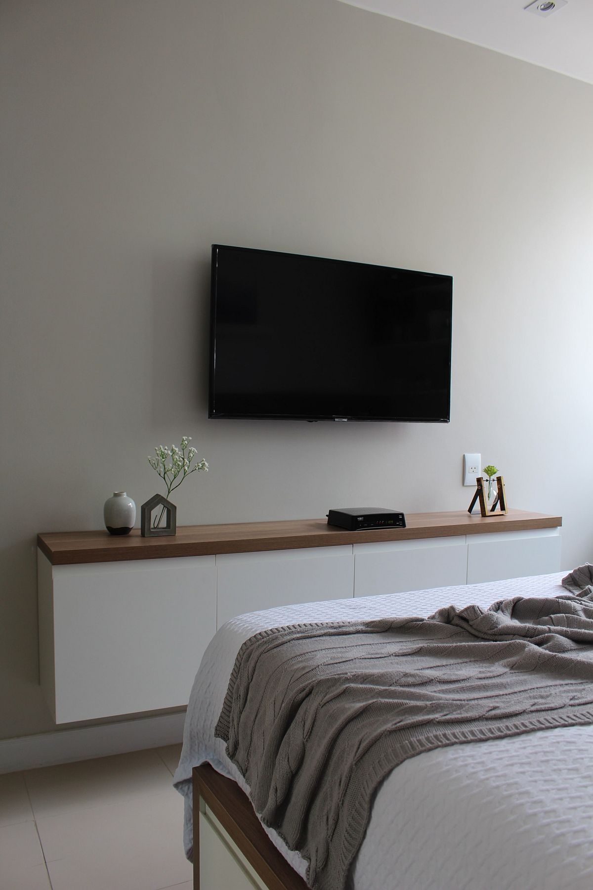 Wall-mounted TV in the bedroom along with a slim storage space below