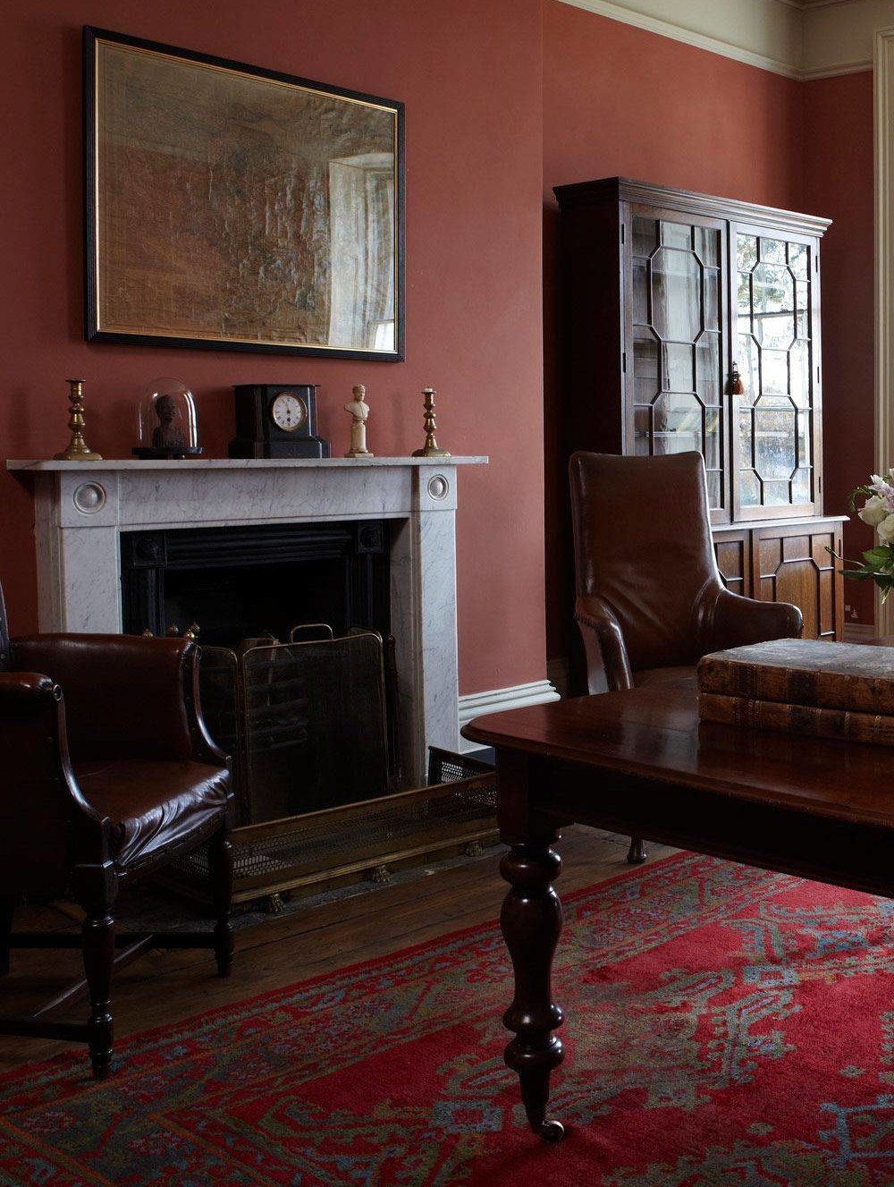 study with brown furniture, red wall and red carpet accent