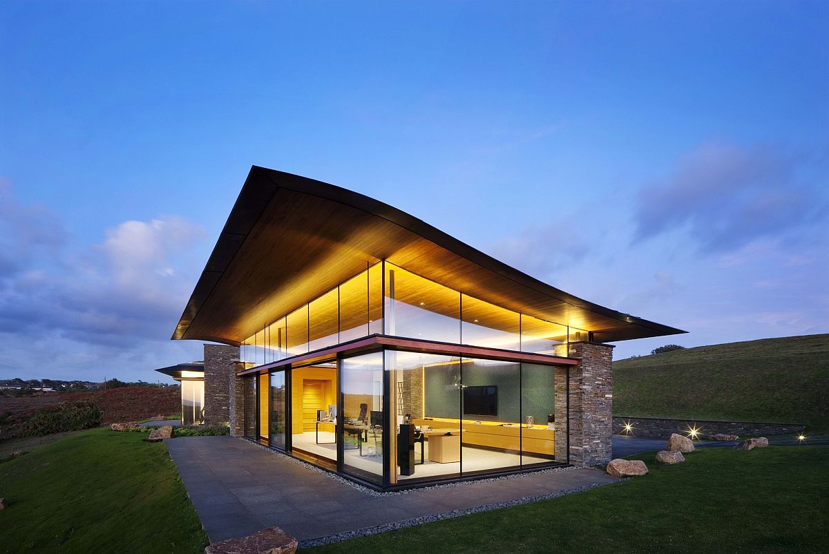 Curvy green roof, natural stone walls and floor-to-ceiling glass windows shape the Logie Point House