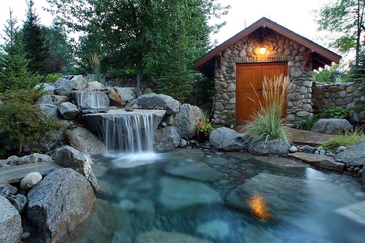 Dreamy rustic landscape with stone waterfall and a lovely wooden shed in the backyard