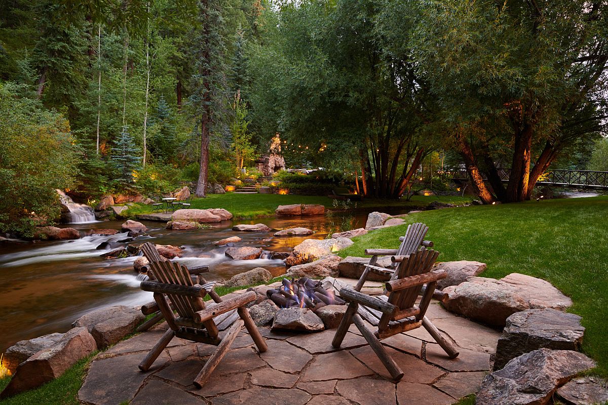 Expansive and relaxing rustic backyard with stone deck, amazing natural water feature and a cozy fireplace