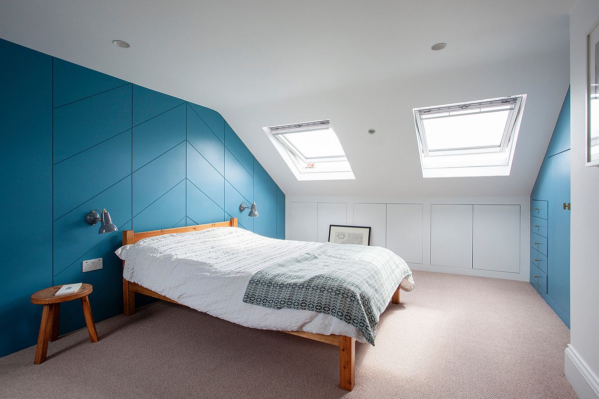 Modern loft bedroom in white with cabinets in blue and a dashing accent wall