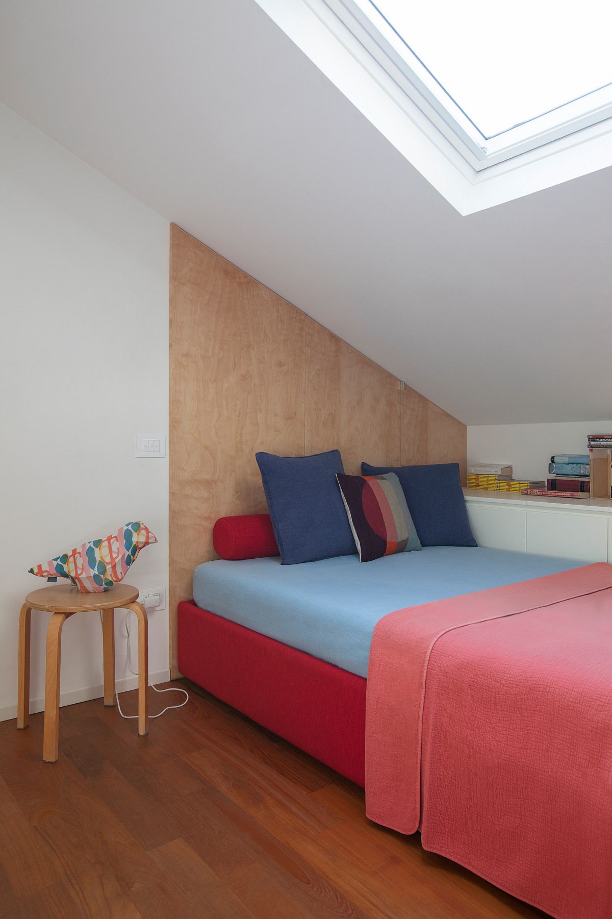 Tiny white and wood bedroom with skylight and bright pink bedding