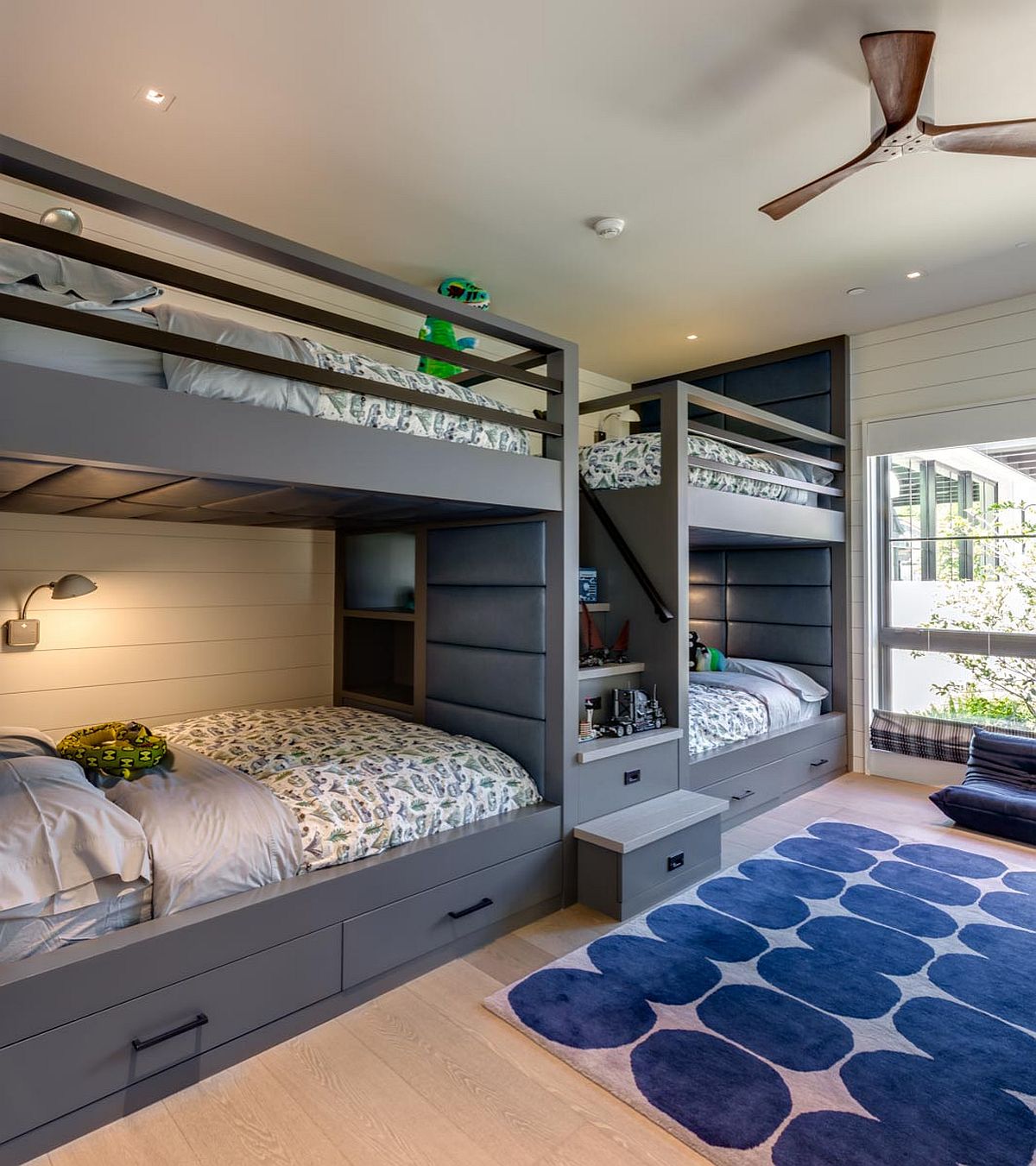 Bespoke wooden bunk beds in gray occupy one side of the room leaving the other free