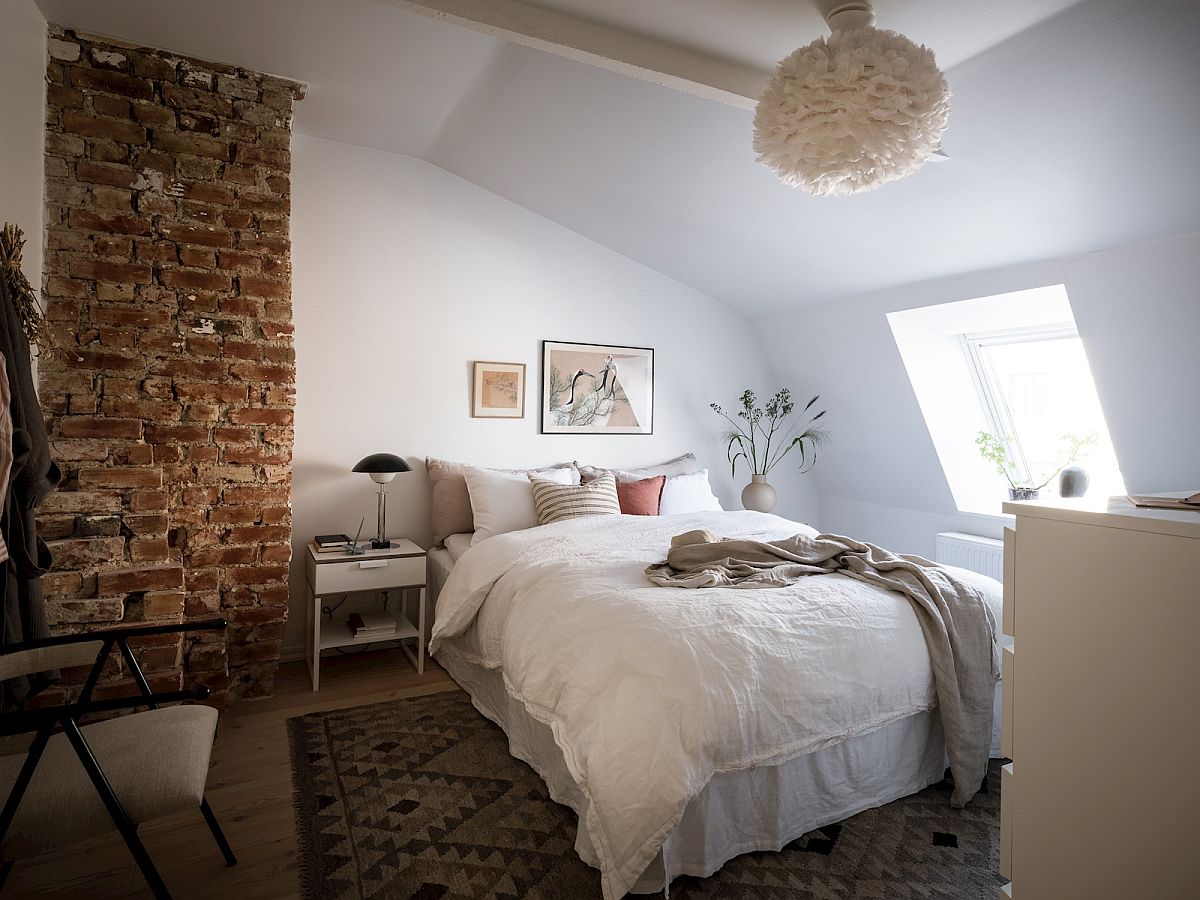 Exposed brick wall section brings an interesting visual and adds contrast to the small bedroom