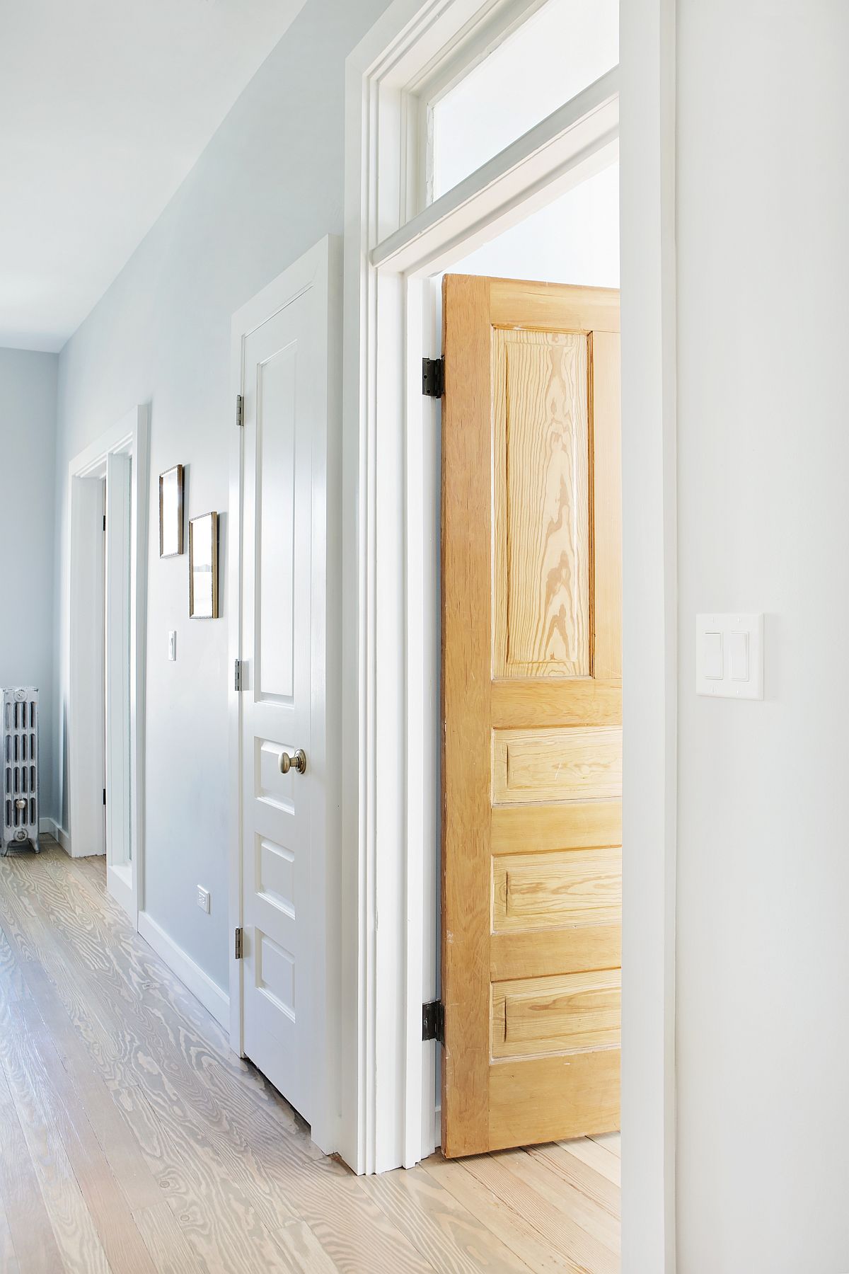 Large hallway of the home in white with ample natural light and wood walls for the room