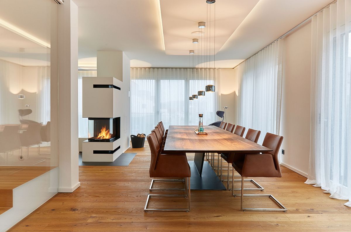 Smart two-sided fireplace becomes the focal point in this all-white modern dining room