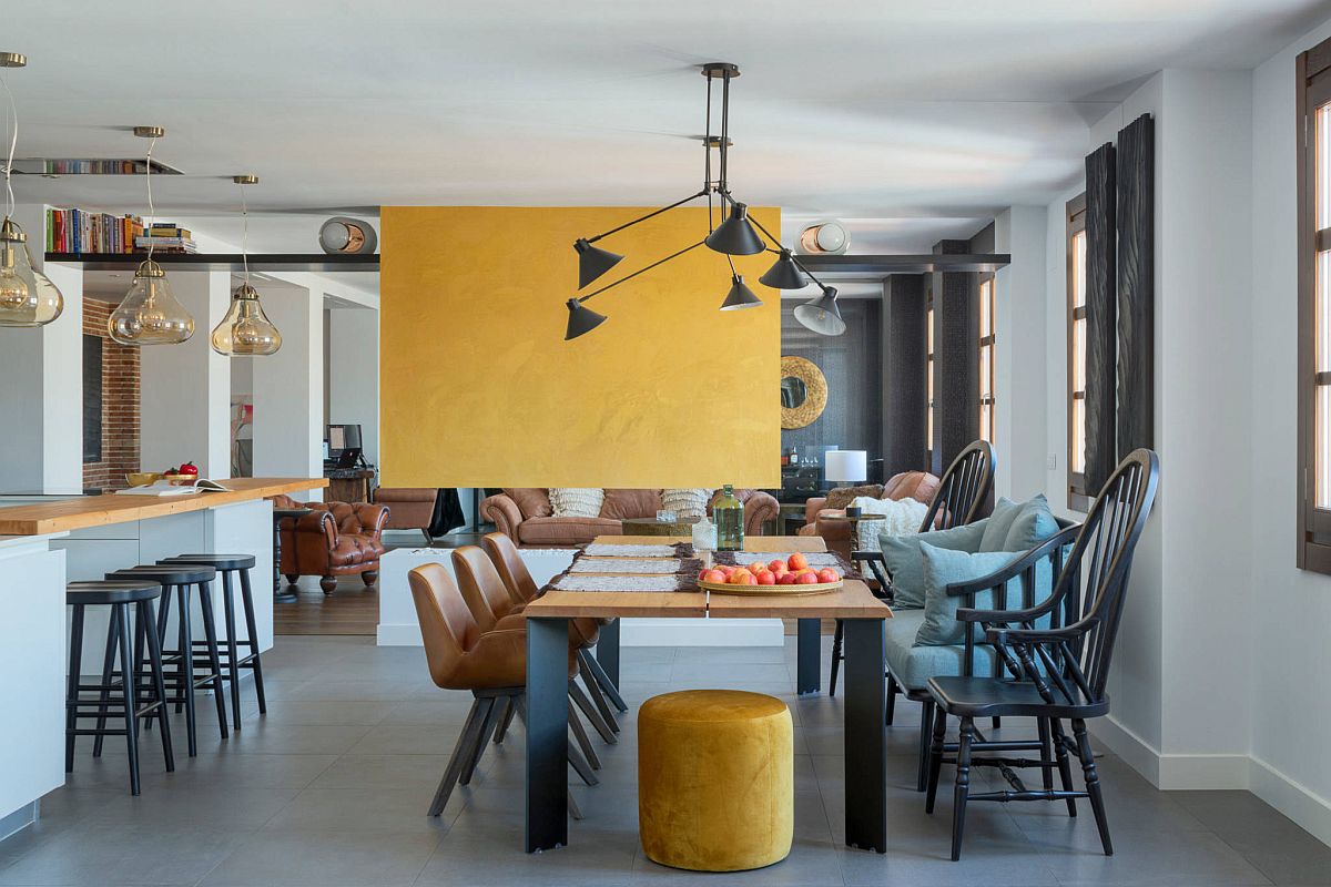 Vibrant yellow fireplace wall brings accent color to this dining room