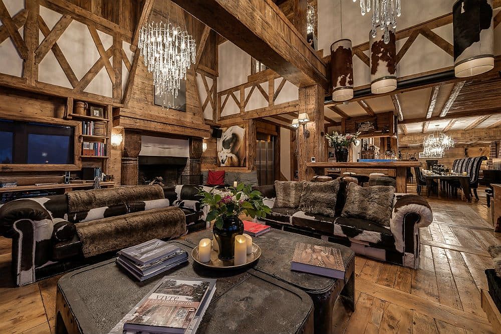 Cozy couches, cowhide rugs and lovely chandeliers create a sense of luxury inside this chalet living room