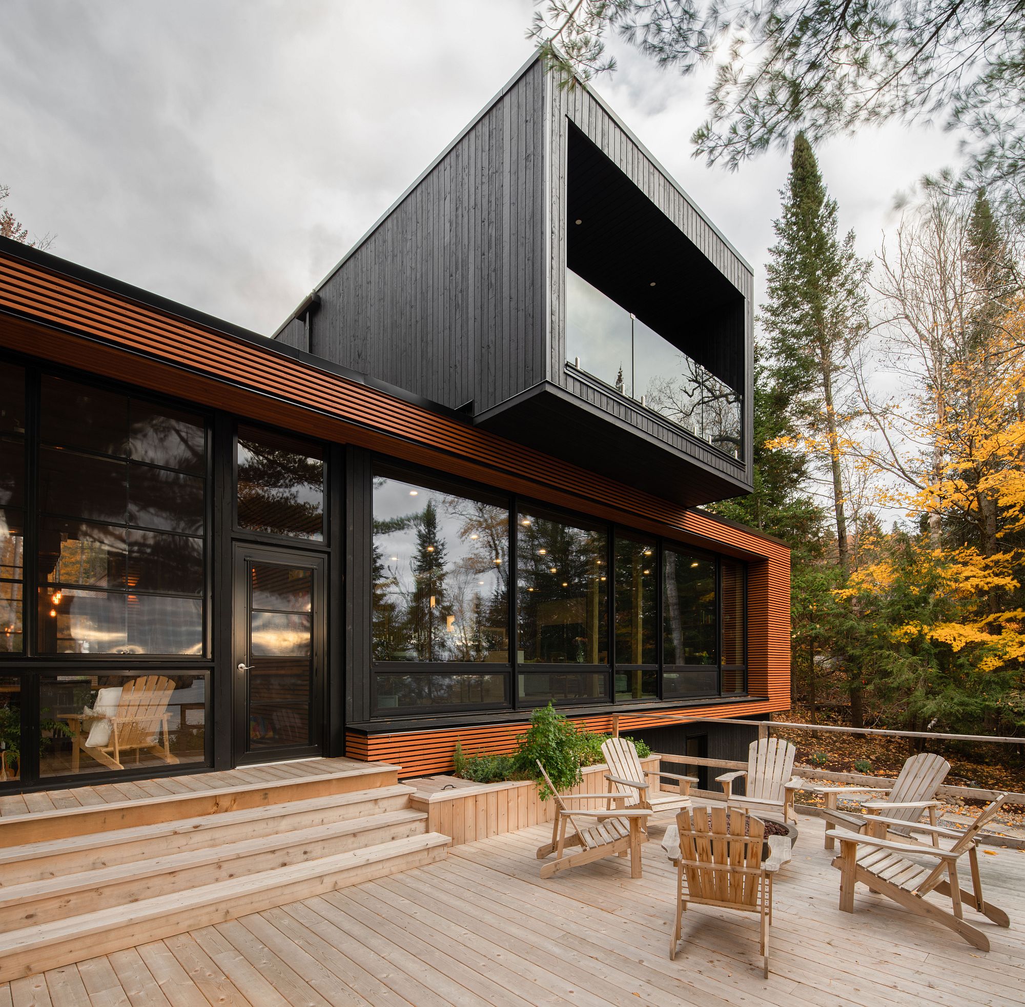 Dark, cantilevered upper level of the house stands in contrast to the lower level with natural finish