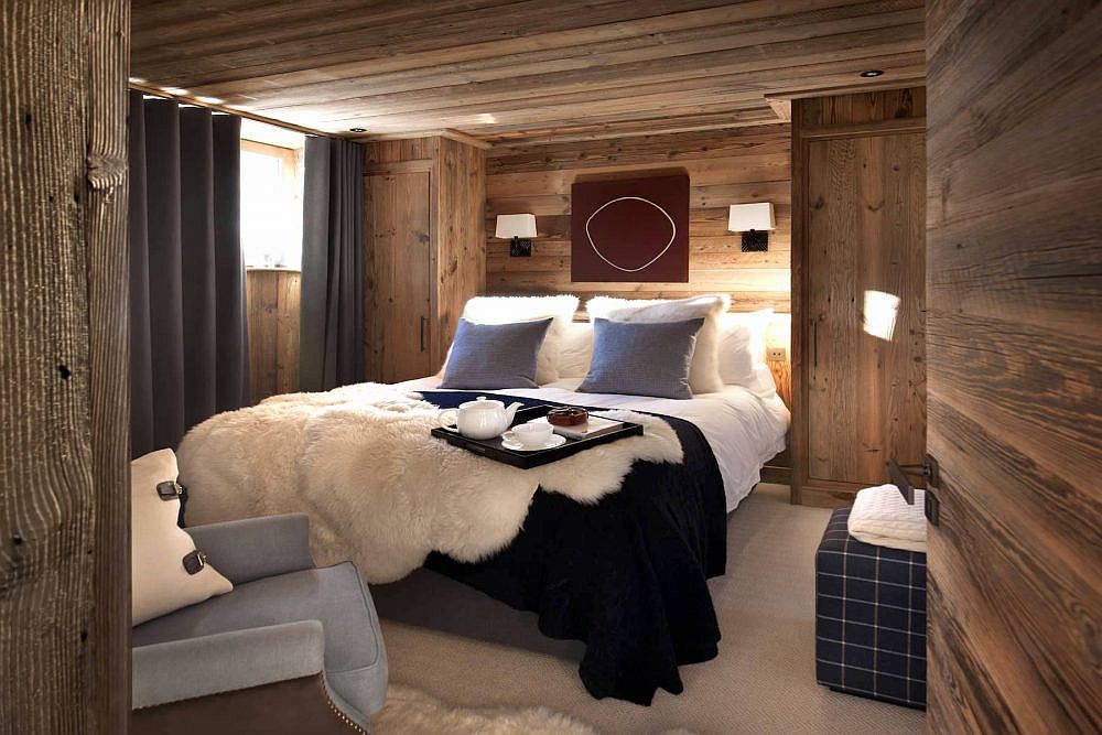 Drapes and pillow colors bring dark bluish-gray to the woodsy cabin-style bedroom