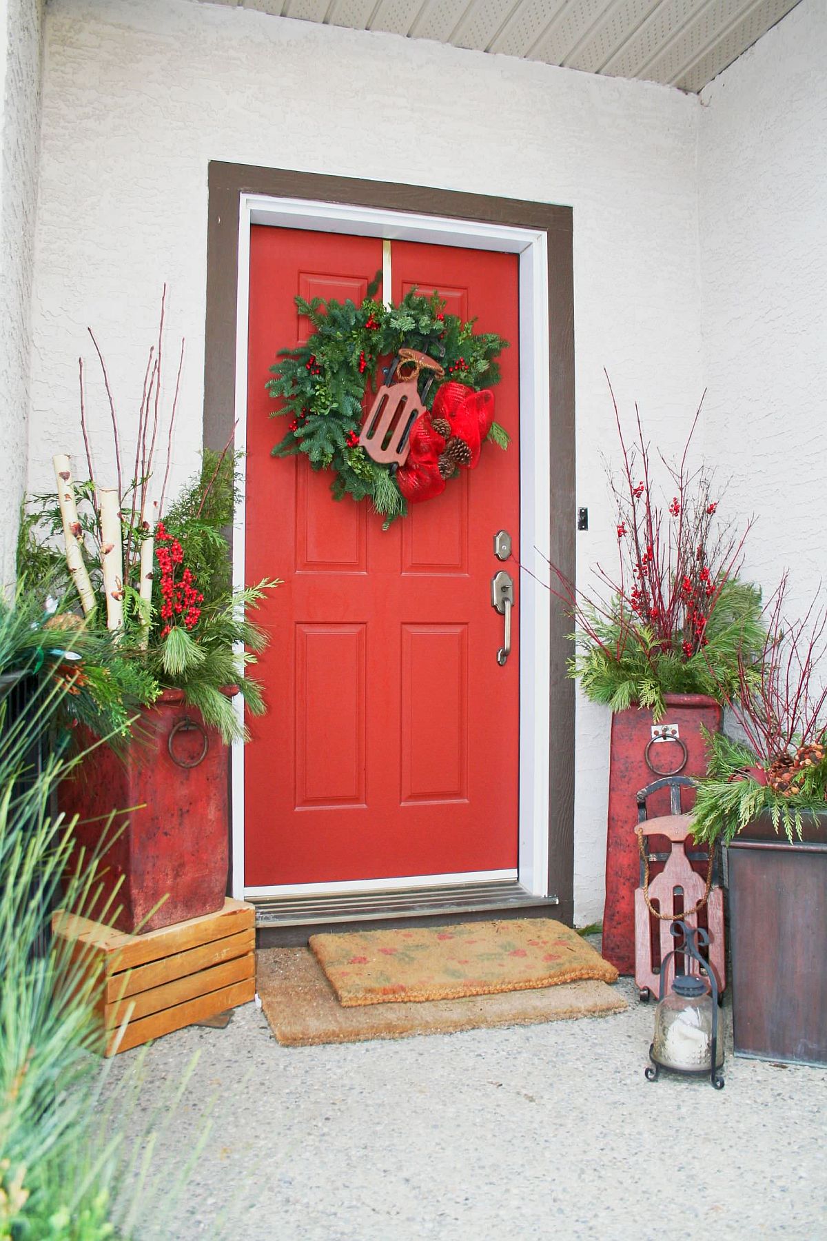 Pops of red added to potted plants and a simple green wreath make a difference to the holiday entry