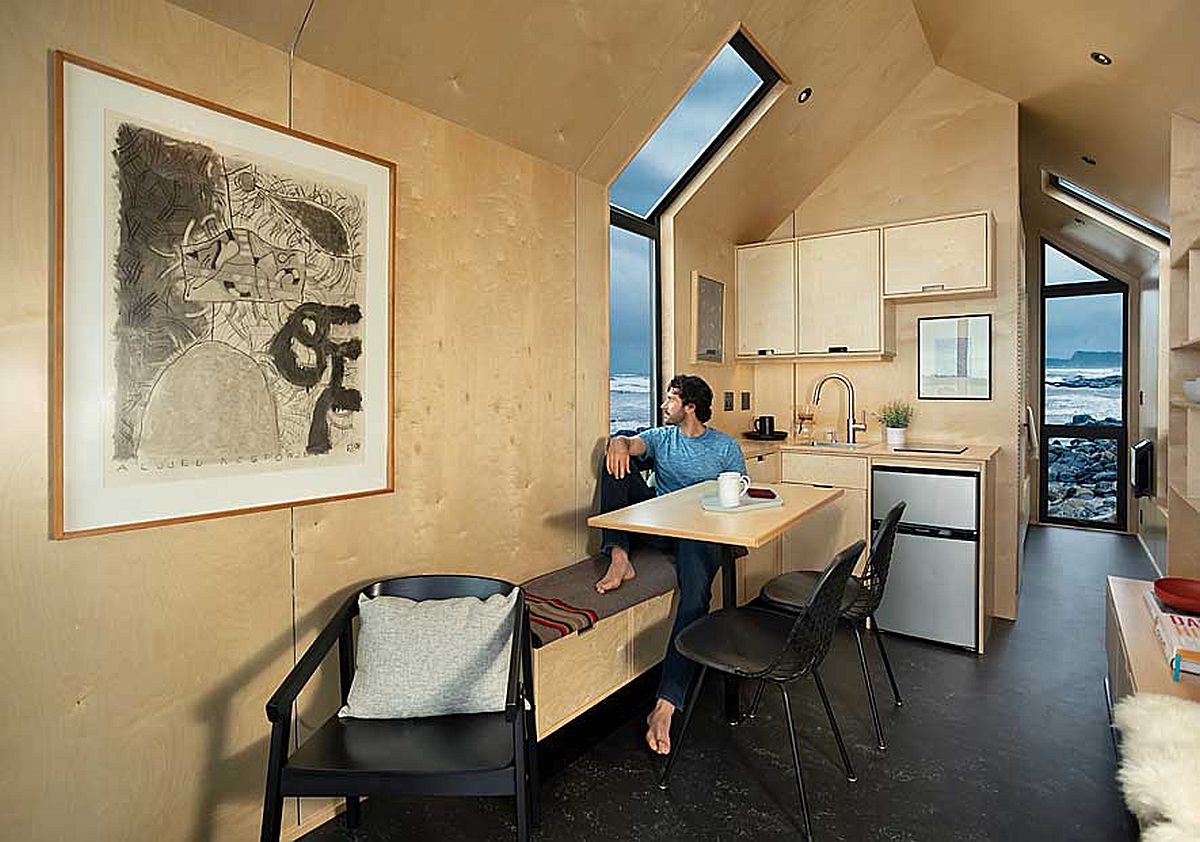Sitting area and small kitchen inside the cabin that is draped in plywood