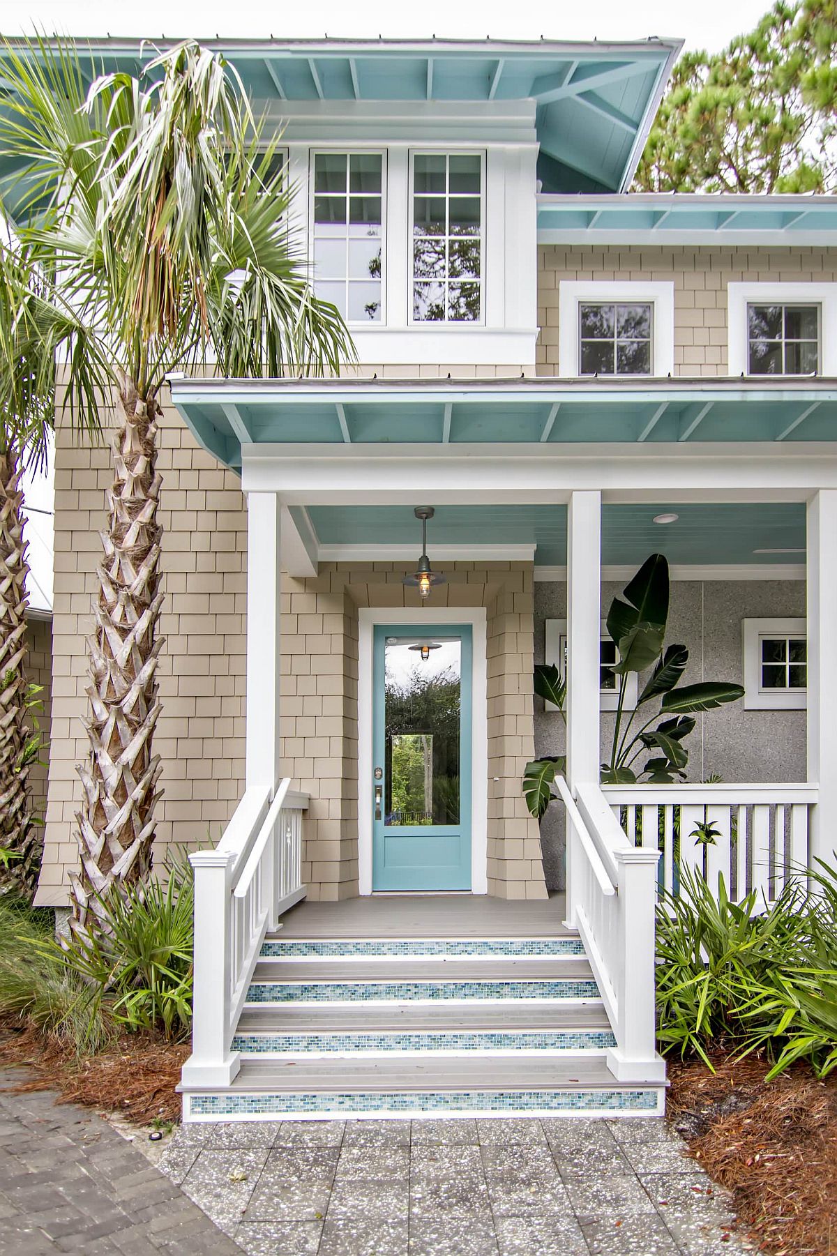 Exquisite pops of light turquoise brighten the street facade of this home in white with a beachy vibe