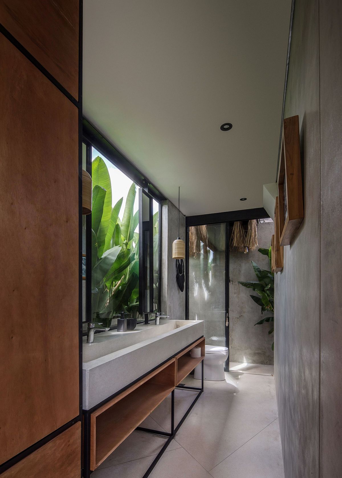 Large banana plants outside become a part ofthe modern minimal bathroom in here