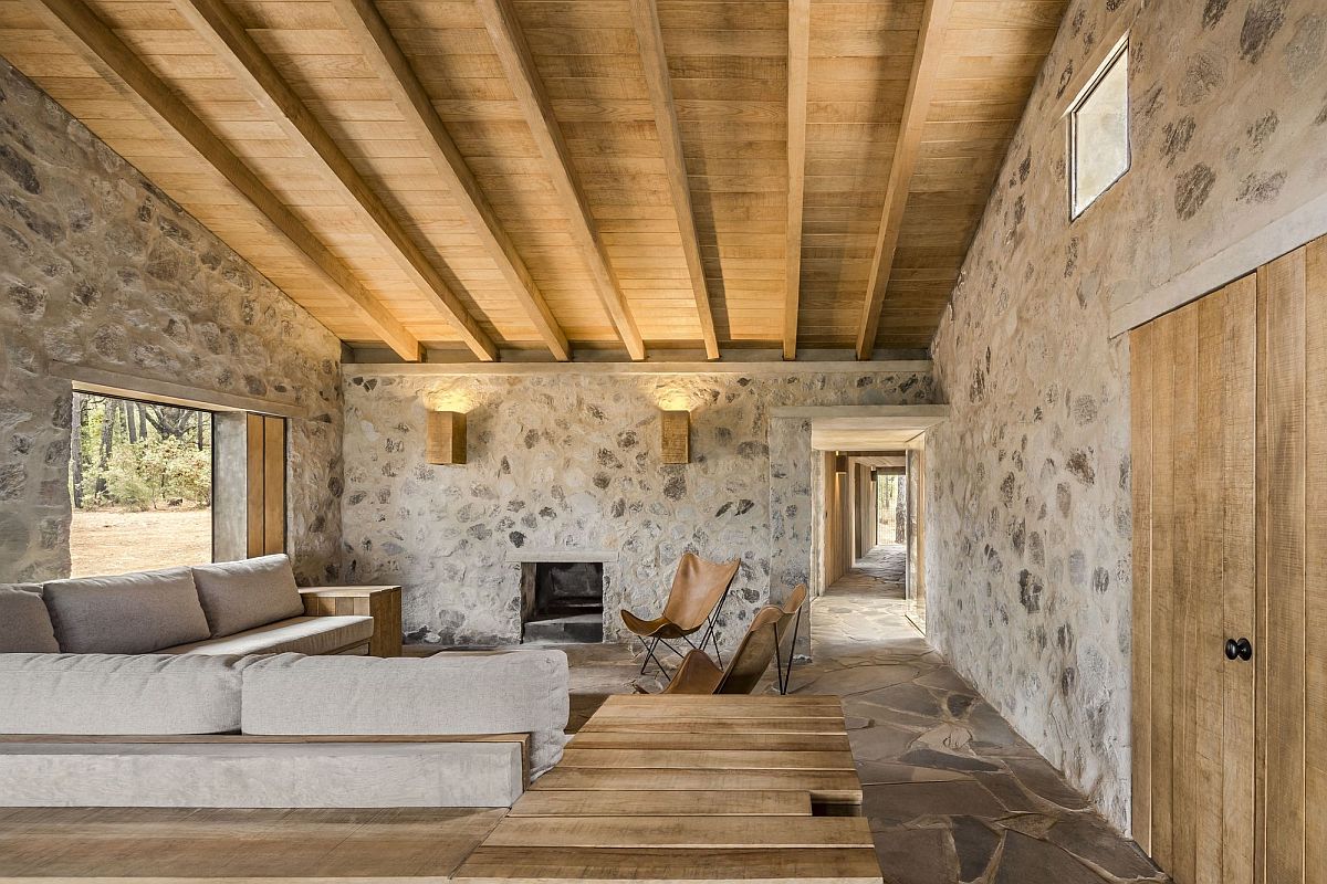 Living area of the cabin with stone walls and a sloped wooden ceiling