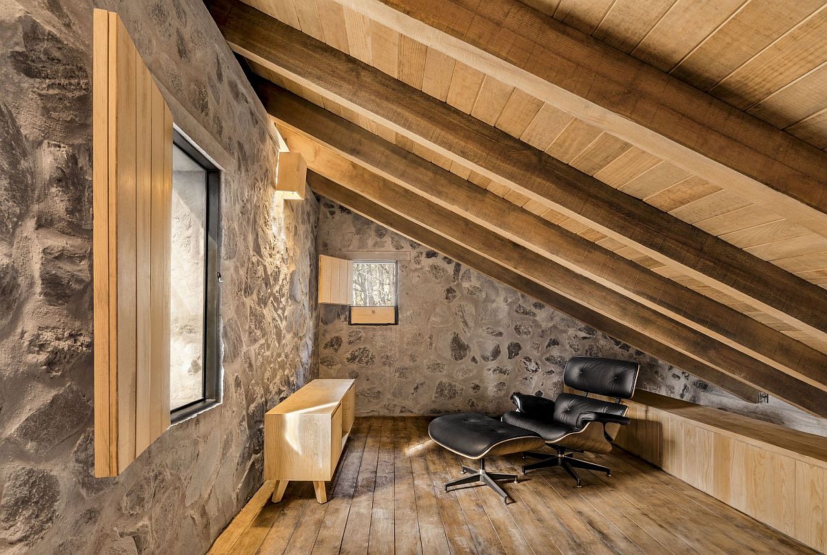 Low and sloping roof of the room leaves little space for the Eames lounger and the small wooden console