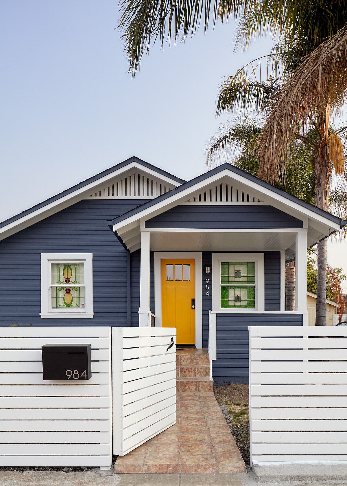 Picture-perfect modern home facade in bluish-gray and white with a dashing and trendy dark yellow door that welcomes you gleefully