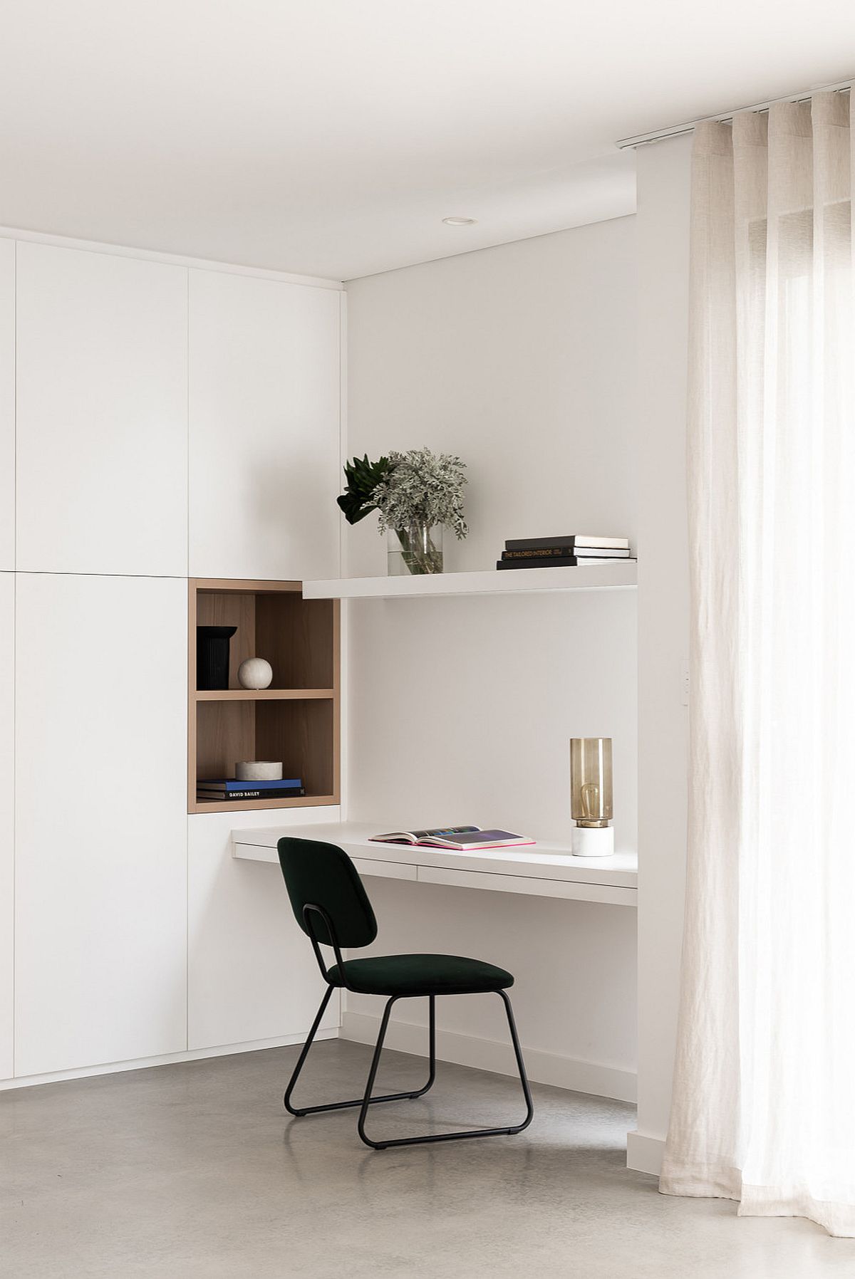 Tiny and minimal workspace in white with a dark chair that adds contrast