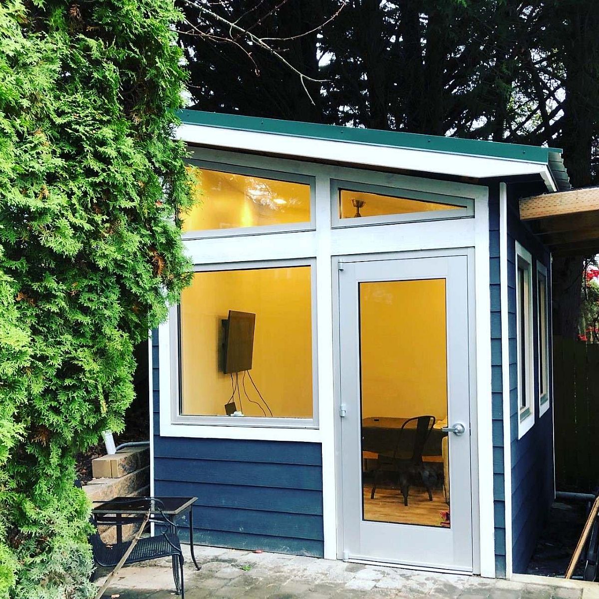 Tiny home office in the backyard with large glass windows that connect it with the world outside