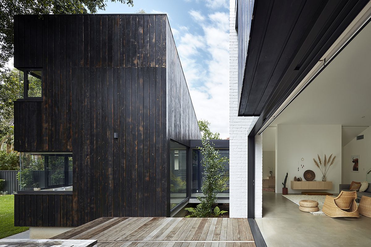 Transition between dark, charred wood finishes and lighter indoor elements is seamless