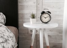 Clock and plant on a white bedside table with three legs